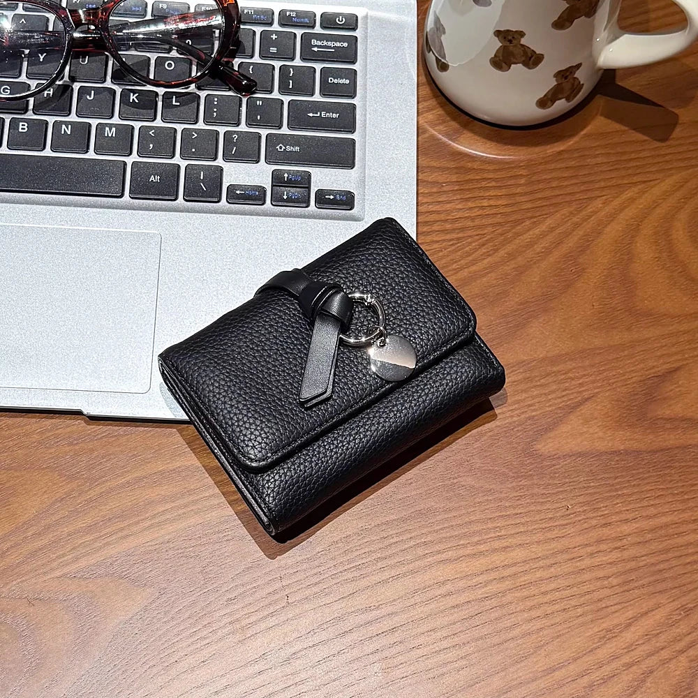 Celia pebbled vegan leather trifold wallet with knotted strap and silver-tone charm