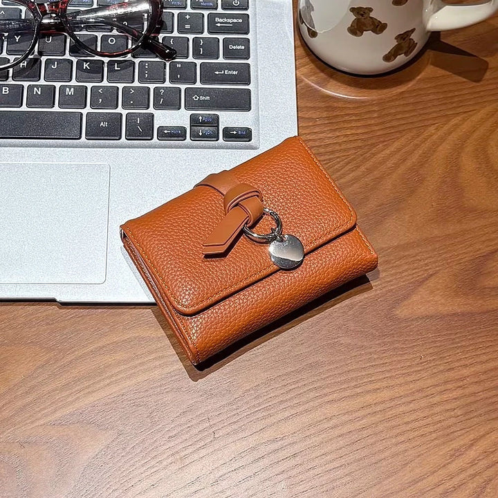 Celia pebbled vegan leather trifold wallet with knotted strap and silver-tone charm