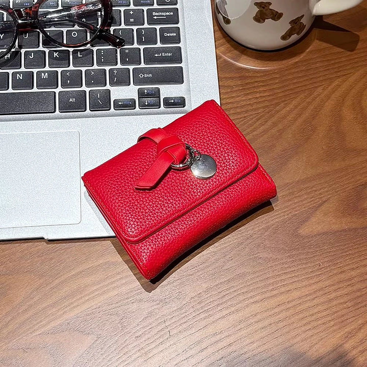 Celia pebbled vegan leather trifold wallet with knotted strap and silver-tone charm