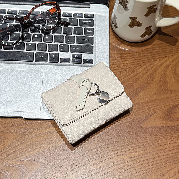 Celia pebbled vegan leather trifold wallet with knotted strap and silver-tone charm