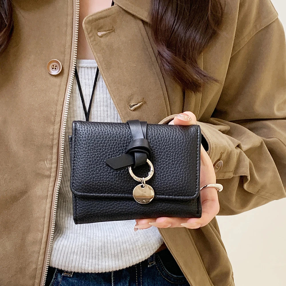 Celia pebbled vegan leather trifold wallet with knotted strap and silver-tone charm