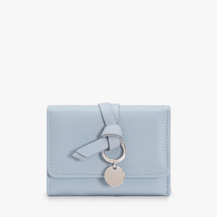 Celia pebbled vegan leather trifold wallet with knotted strap and silver-tone charm in Light Blue