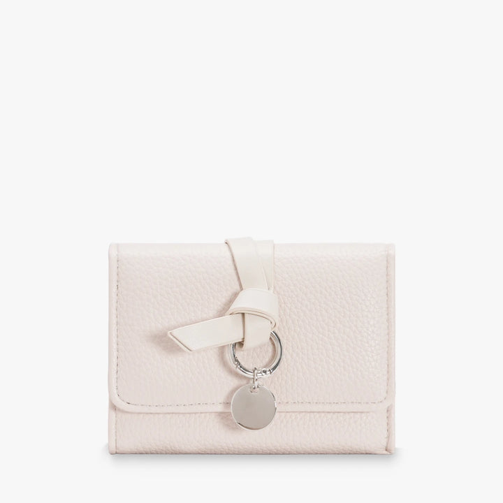 Celia pebbled vegan leather trifold wallet with knotted strap and silver-tone charm in Cream