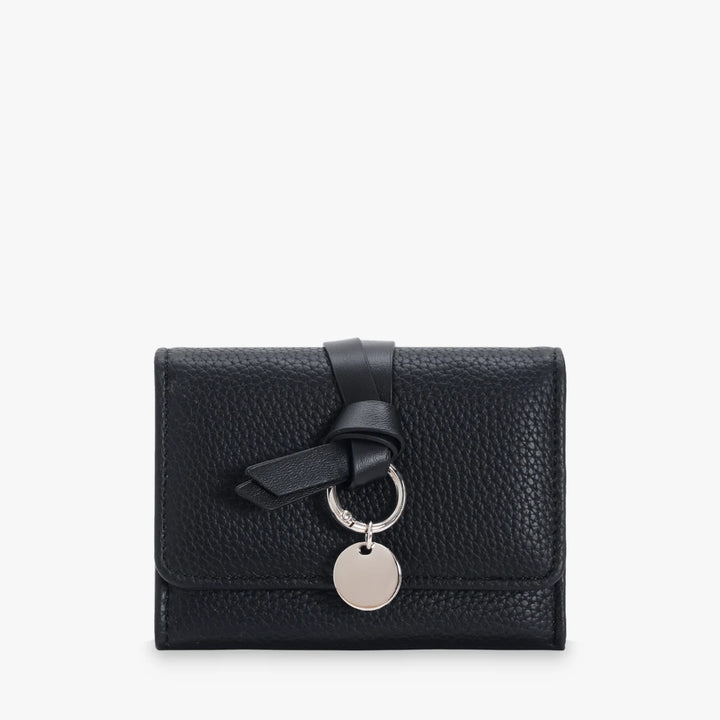 Celia pebbled vegan leather trifold wallet with knotted strap and silver-tone charm in Black